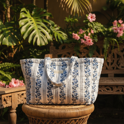 Floral-patterned tote bag on a wicker stool with plants and flowers in the background
