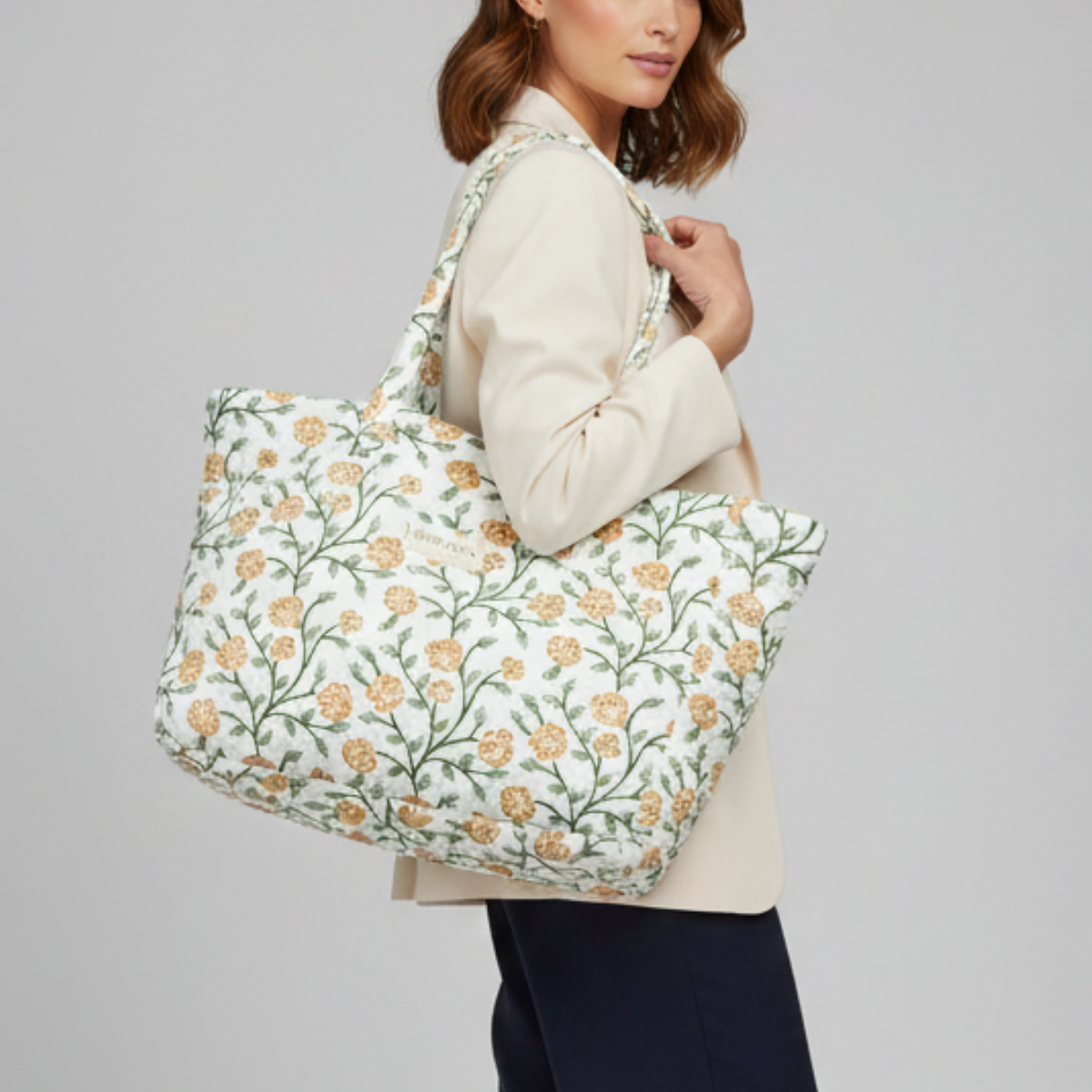 Woman holding a floral-patterned tote bag against a gray background