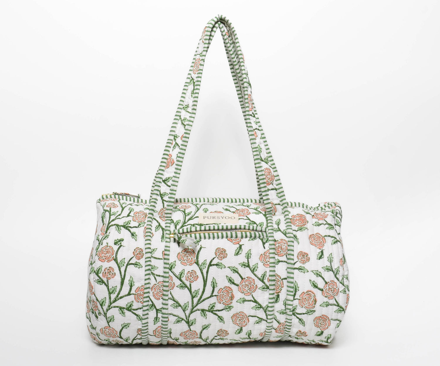 A quilted cotton duffel bag with hand block printed floral vine designs in peach blush and green colors, featuring a zip closure and an exterior one zipper pocket.